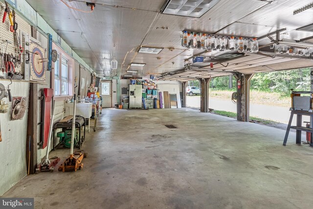 garage featuring a workshop area and stainless steel refrigerator with ice dispenser