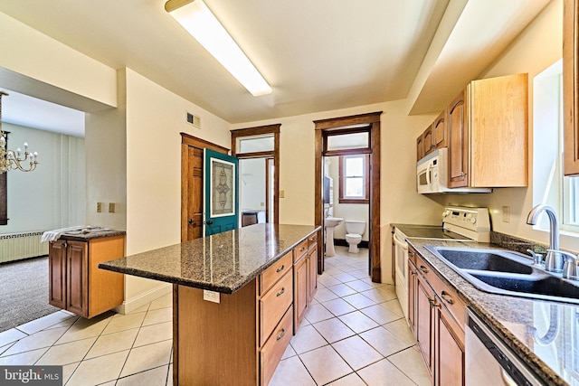 kitchen with light tile patterned flooring, white appliances, a sink, visible vents, and a center island