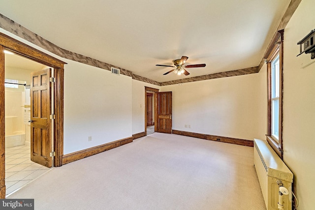 unfurnished room featuring a wealth of natural light, light colored carpet, visible vents, a ceiling fan, and baseboards