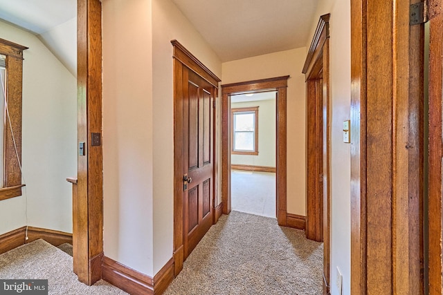 corridor with carpet floors and vaulted ceiling