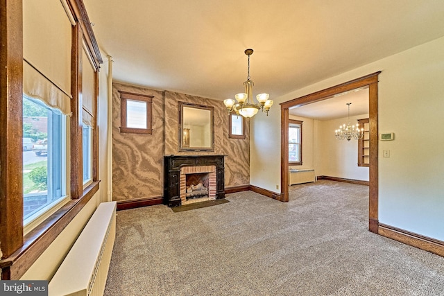 unfurnished living room with carpet flooring, a brick fireplace, an inviting chandelier, and plenty of natural light