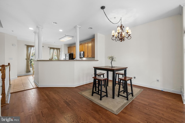 dining space with decorative columns, baseboards, wood finished floors, a notable chandelier, and recessed lighting