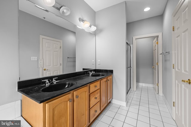 bathroom featuring double vanity, a stall shower, and a sink