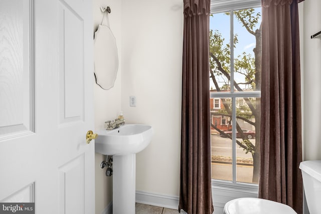 bathroom featuring toilet, baseboards, and a sink