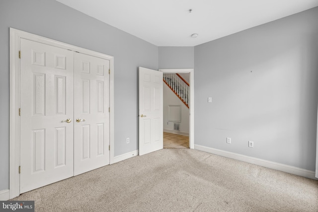 unfurnished bedroom with carpet, a closet, visible vents, and baseboards