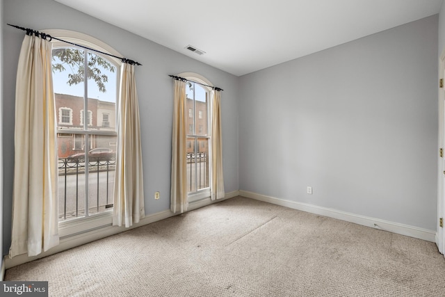 carpeted spare room featuring visible vents and baseboards