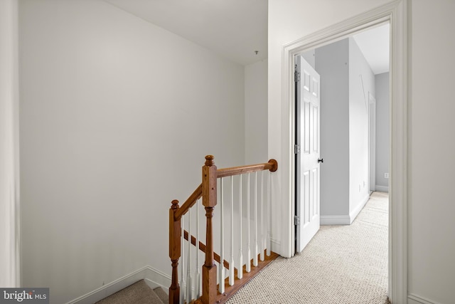 hall with carpet, an upstairs landing, and baseboards