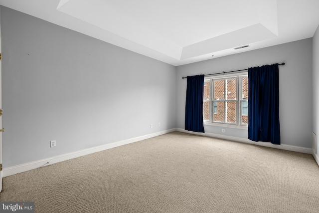 carpeted empty room featuring baseboards, visible vents, and a raised ceiling