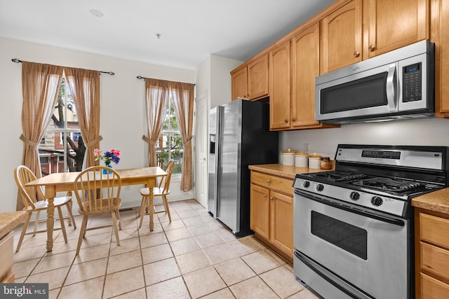 kitchen with light tile patterned floors, stainless steel appliances, light countertops, and baseboards