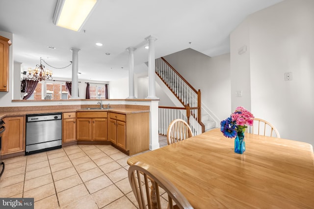 kitchen featuring light tile patterned floors, stainless steel dishwasher, a sink, a peninsula, and ornate columns