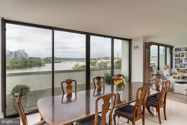 tiled dining area featuring a water view and a wall of windows