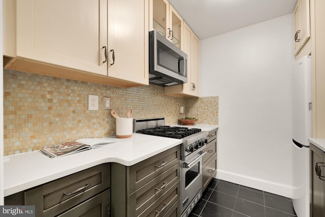 kitchen with backsplash, dark brown cabinetry, dark tile patterned floors, and stainless steel appliances