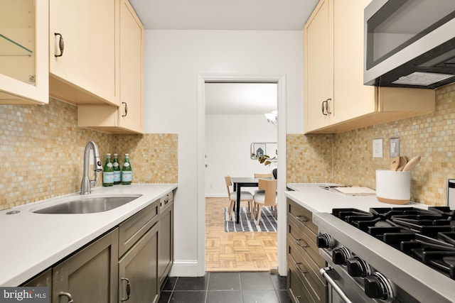 kitchen featuring tasteful backsplash, stainless steel range, sink, dark tile patterned flooring, and cream cabinetry