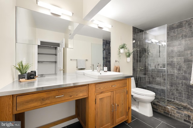 bathroom featuring tile patterned flooring, vanity, toilet, and tiled shower