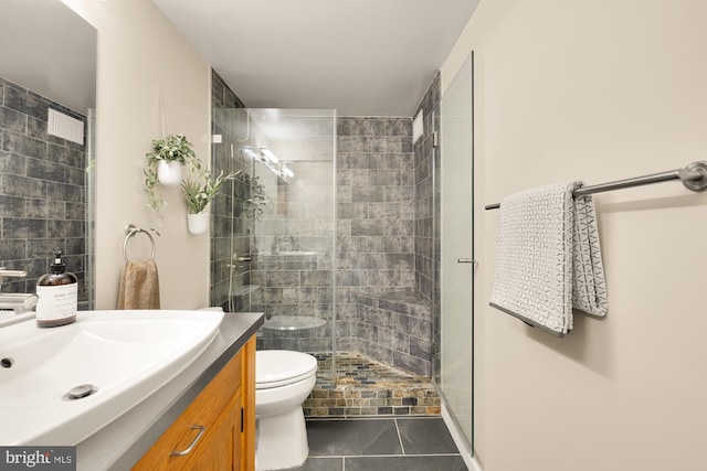 bathroom with tile patterned floors, vanity, toilet, and a shower with door