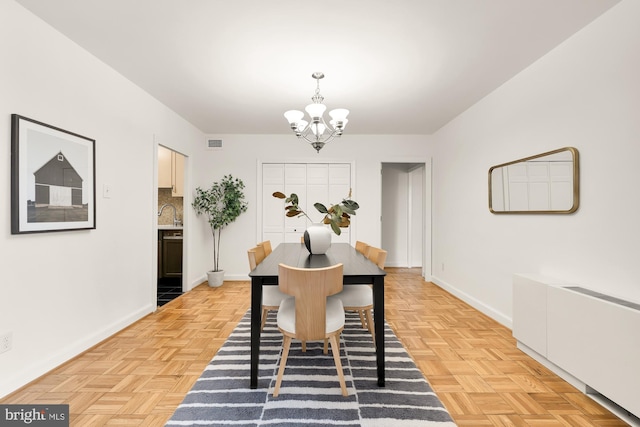 dining room featuring light parquet flooring and a notable chandelier