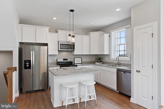 kitchen with sink, a center island, stainless steel appliances, hardwood / wood-style floors, and pendant lighting