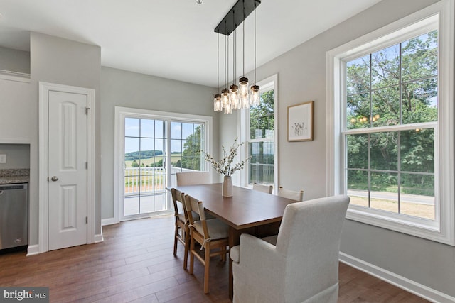 dining space with dark hardwood / wood-style floors, plenty of natural light, and a notable chandelier