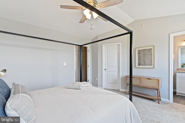 bedroom with carpet floors, ensuite bathroom, vaulted ceiling, and ceiling fan