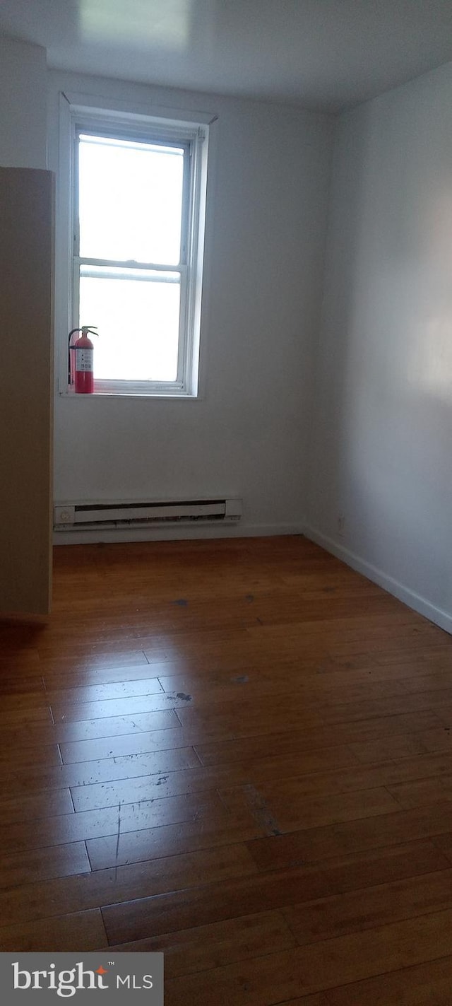 unfurnished room featuring a baseboard radiator and dark hardwood / wood-style floors