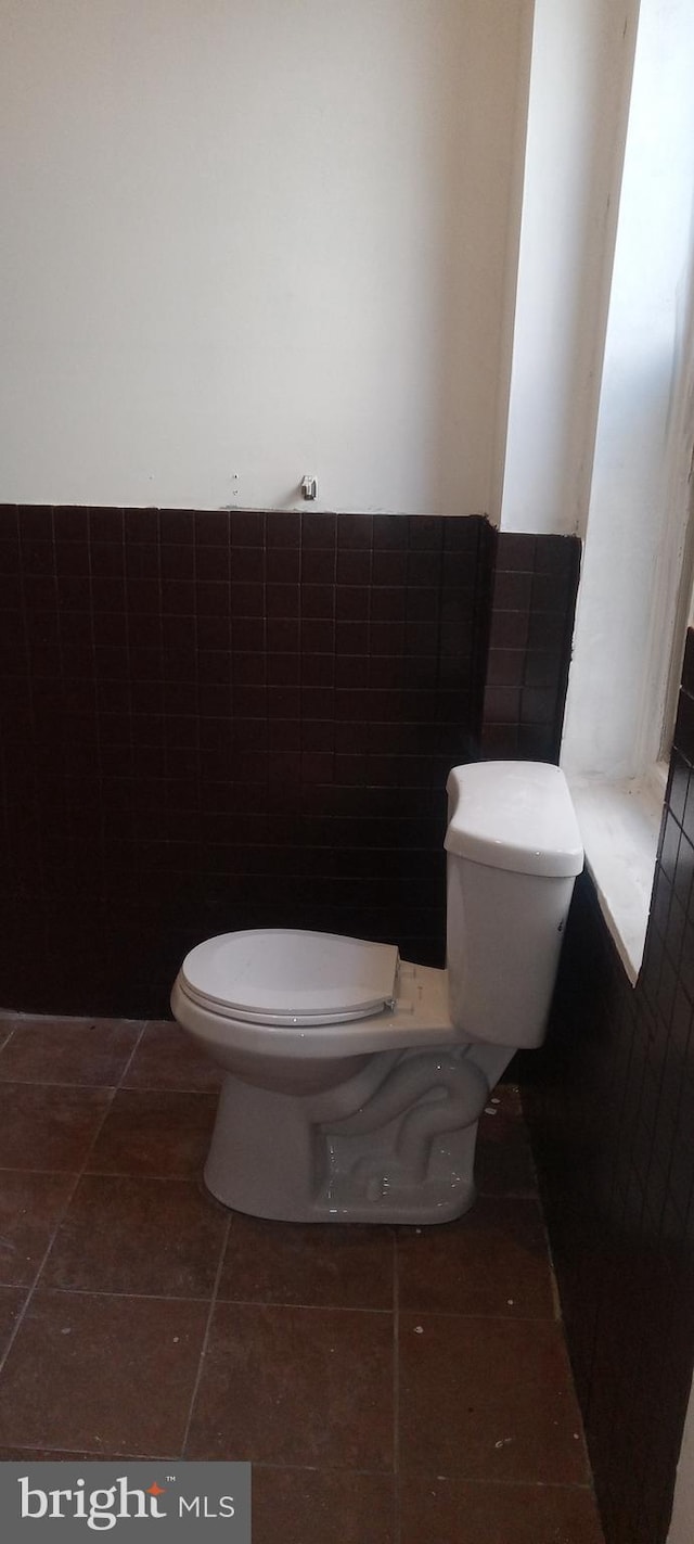 bathroom featuring tile patterned floors, toilet, and tile walls