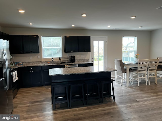 kitchen with a kitchen breakfast bar, a kitchen island, light stone counters, and light hardwood / wood-style floors