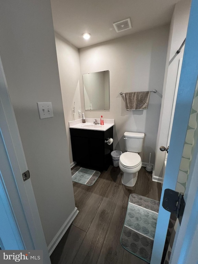 bathroom with vanity, toilet, and wood-type flooring