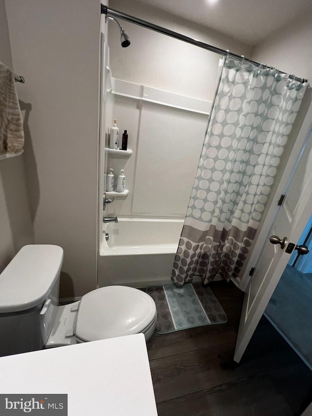 bathroom featuring toilet, hardwood / wood-style floors, and shower / tub combo with curtain