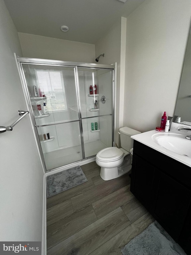 bathroom featuring vanity, toilet, and a shower with door