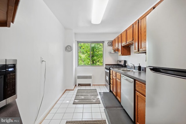 kitchen featuring radiator, sink, light tile patterned floors, and stainless steel appliances