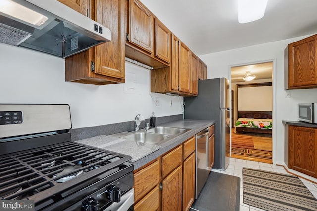 kitchen with appliances with stainless steel finishes, sink, light tile patterned floors, and exhaust hood