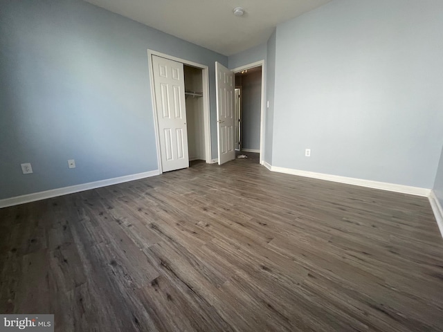 unfurnished bedroom featuring a closet and dark hardwood / wood-style flooring