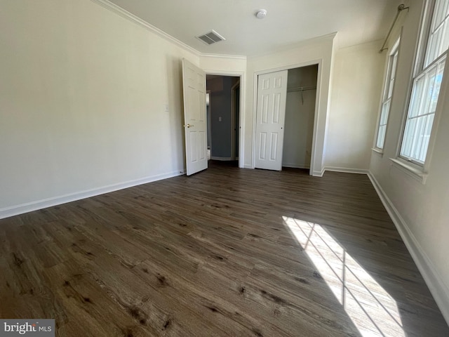 unfurnished bedroom with crown molding, dark wood-type flooring, and a closet