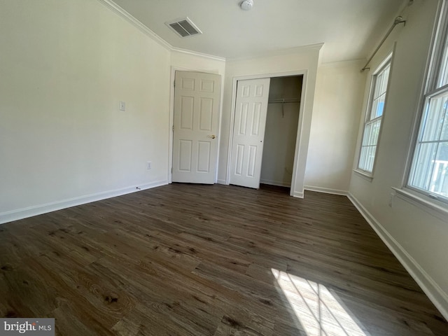 unfurnished bedroom featuring multiple windows, a closet, dark hardwood / wood-style floors, and ornamental molding