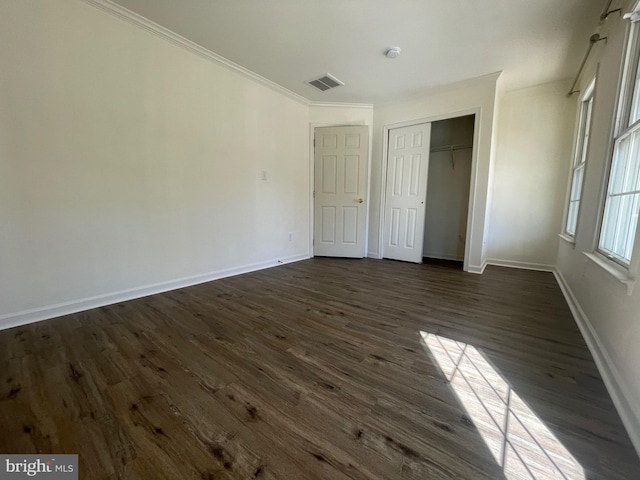 unfurnished bedroom with a closet, dark hardwood / wood-style floors, and ornamental molding