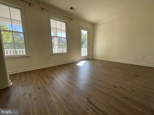 unfurnished room featuring dark hardwood / wood-style floors, plenty of natural light, and ornamental molding