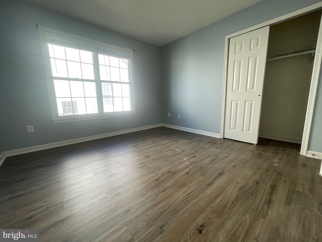 unfurnished bedroom with a closet and dark hardwood / wood-style flooring