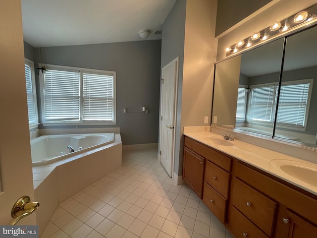 bathroom featuring tile patterned flooring, vanity, and tiled tub