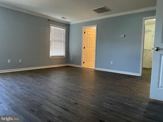 empty room featuring dark wood-type flooring and ornamental molding