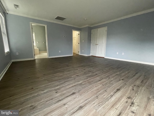 unfurnished bedroom featuring hardwood / wood-style floors, crown molding, and connected bathroom