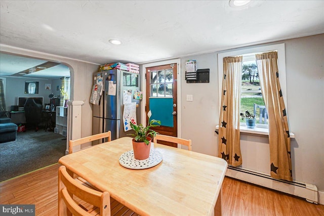 dining space with light hardwood / wood-style flooring and a baseboard heating unit