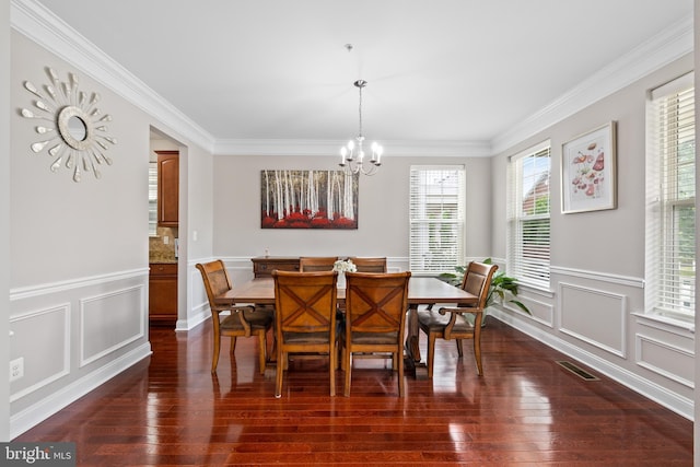 dining room with crown molding, dark wood-type flooring, visible vents, and a notable chandelier
