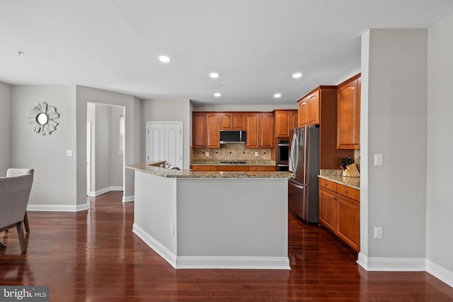 kitchen featuring light stone countertops, a center island with sink, appliances with stainless steel finishes, and backsplash