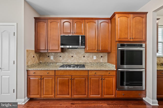 kitchen featuring appliances with stainless steel finishes, decorative backsplash, and light stone counters