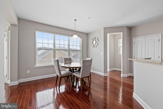 dining space with baseboards and dark wood finished floors