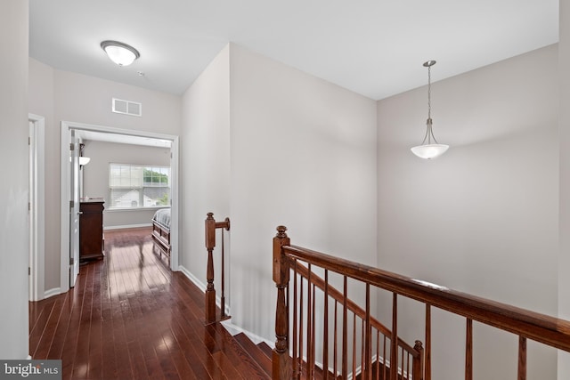 hall featuring dark wood finished floors, an upstairs landing, visible vents, and baseboards