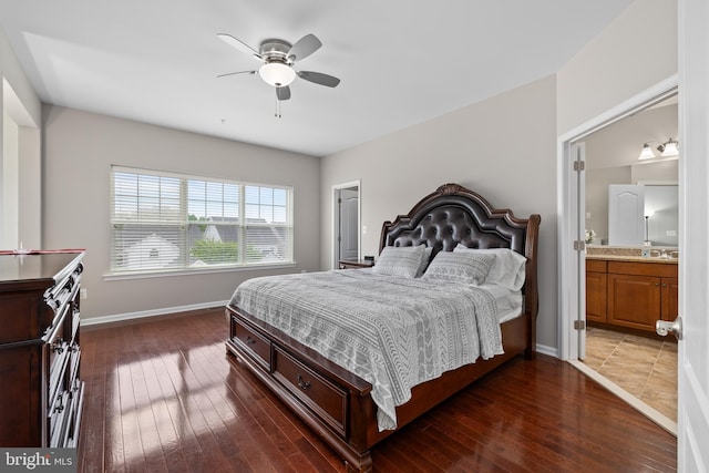 bedroom featuring ensuite bathroom, dark wood-type flooring, a ceiling fan, and baseboards