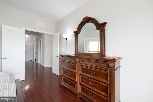 corridor featuring dark wood-style floors, visible vents, and baseboards