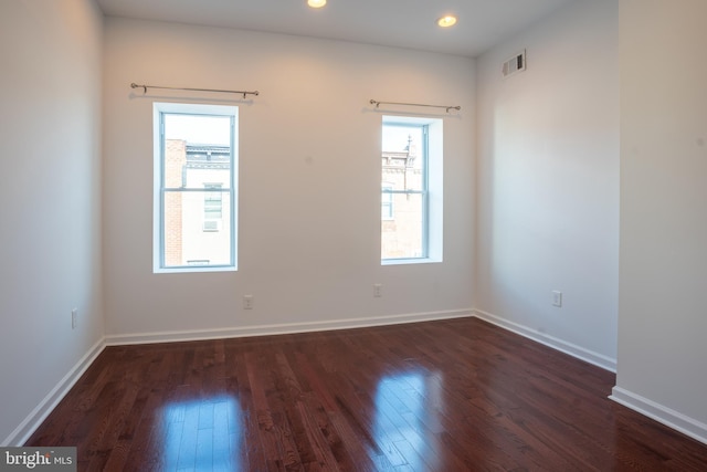 empty room with a healthy amount of sunlight and dark hardwood / wood-style flooring