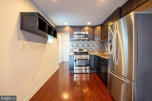 kitchen with dark wood-type flooring, dark brown cabinets, stainless steel appliances, light stone counters, and tasteful backsplash